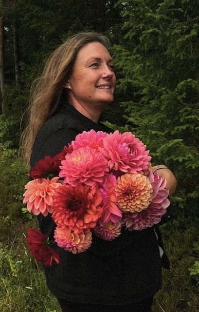 Anette med famnen full av rosa och röda dahlior