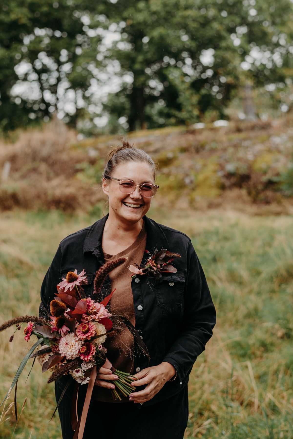 Anette i jeansjacka håller en bukett i rost och rosa
